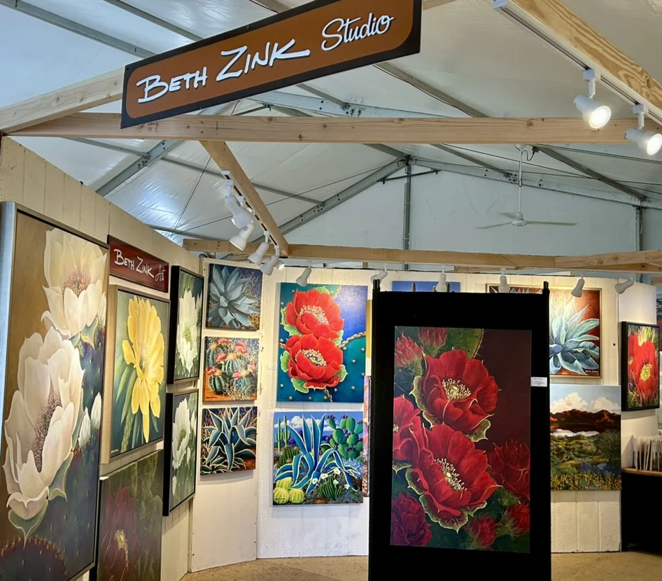 Beth Zink Studio features vibrant floral paintings of cacti and large blossoms in an art exhibition tent.